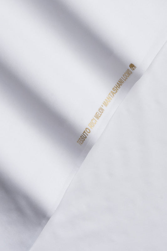 White fabric with gold text and logo on a light gray background
